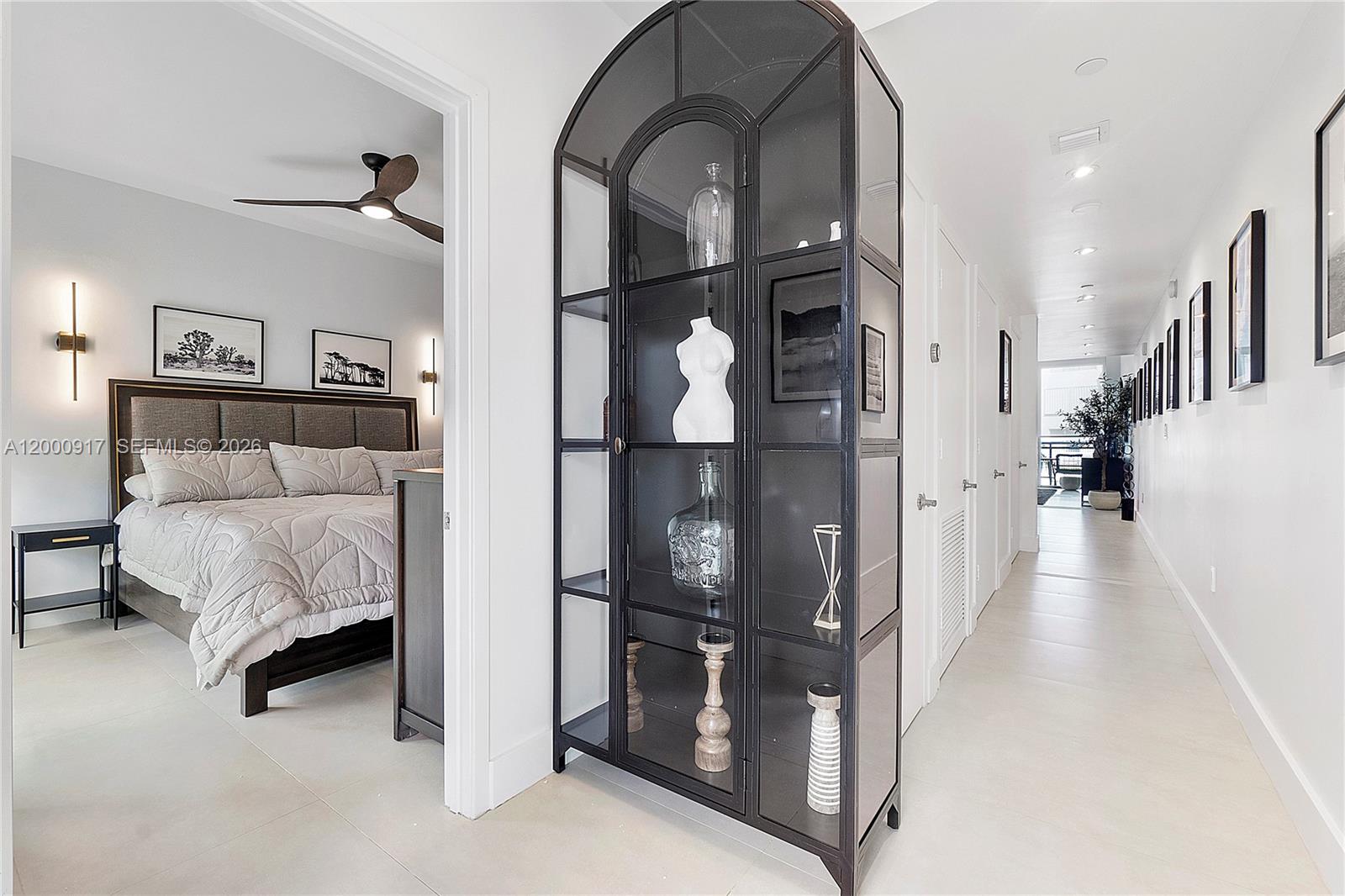 A bedroom entrance sits beside a tall, arched black metal display cabinet in a hallway — 6000 Collins Ave # 527, Miami Beach FL 33140, MIAMI BEACH, FL