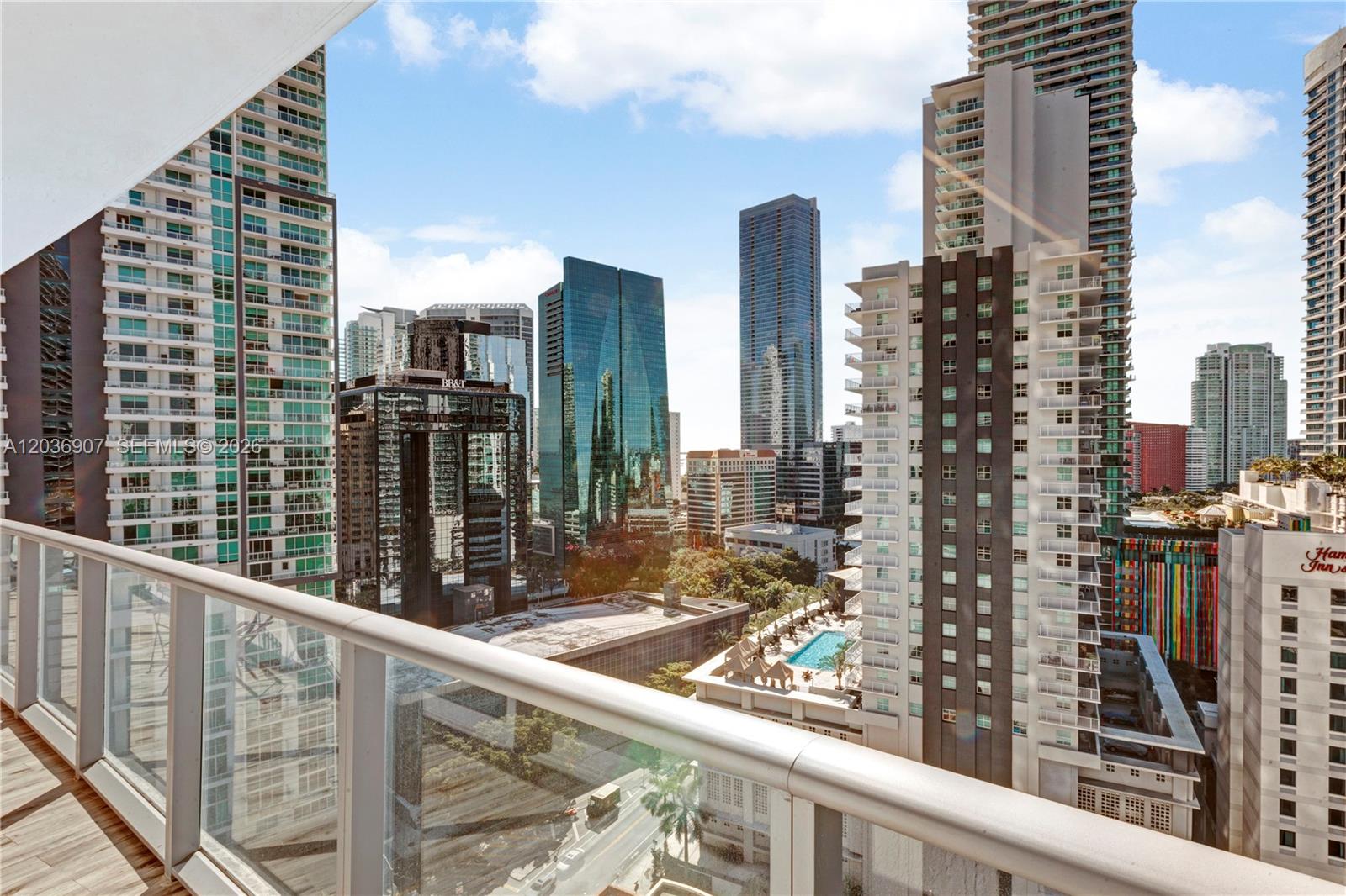 A high-rise balcony overlooks a dense urban cityscape with multiple skyscrapers and a swimming pool — 1100 S Miami Ave # 1804, Miami FL 33130, MIAMI, FL