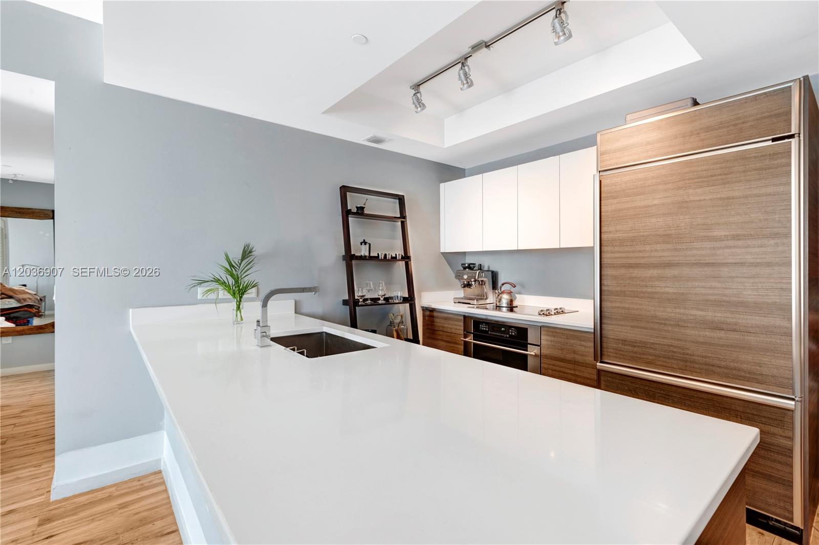 A modern kitchen features white countertops, wood-toned cabinetry, and a stainless steel refrigerator — 1100 S Miami Ave # 1804, Miami FL 33130, MIAMI, FL