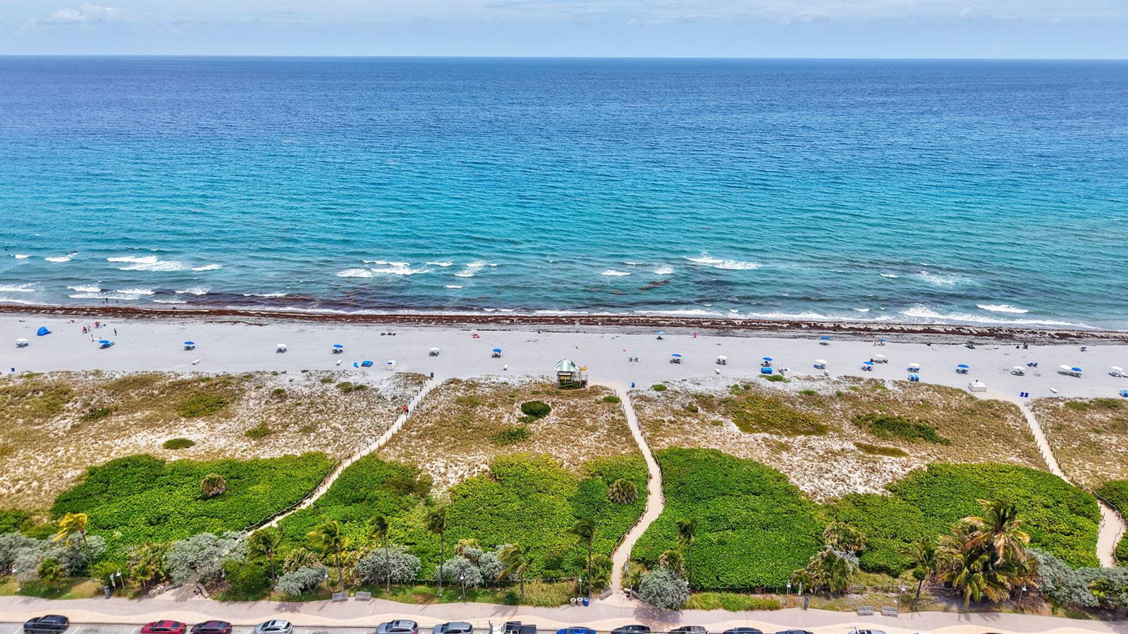 An aerial view shows a sandy beach with dunes, walkways, and the ocean beyond — 100 N Ocean Boulevard # 105, Delray Beach FL 33483, DELRAY BEACH, FL