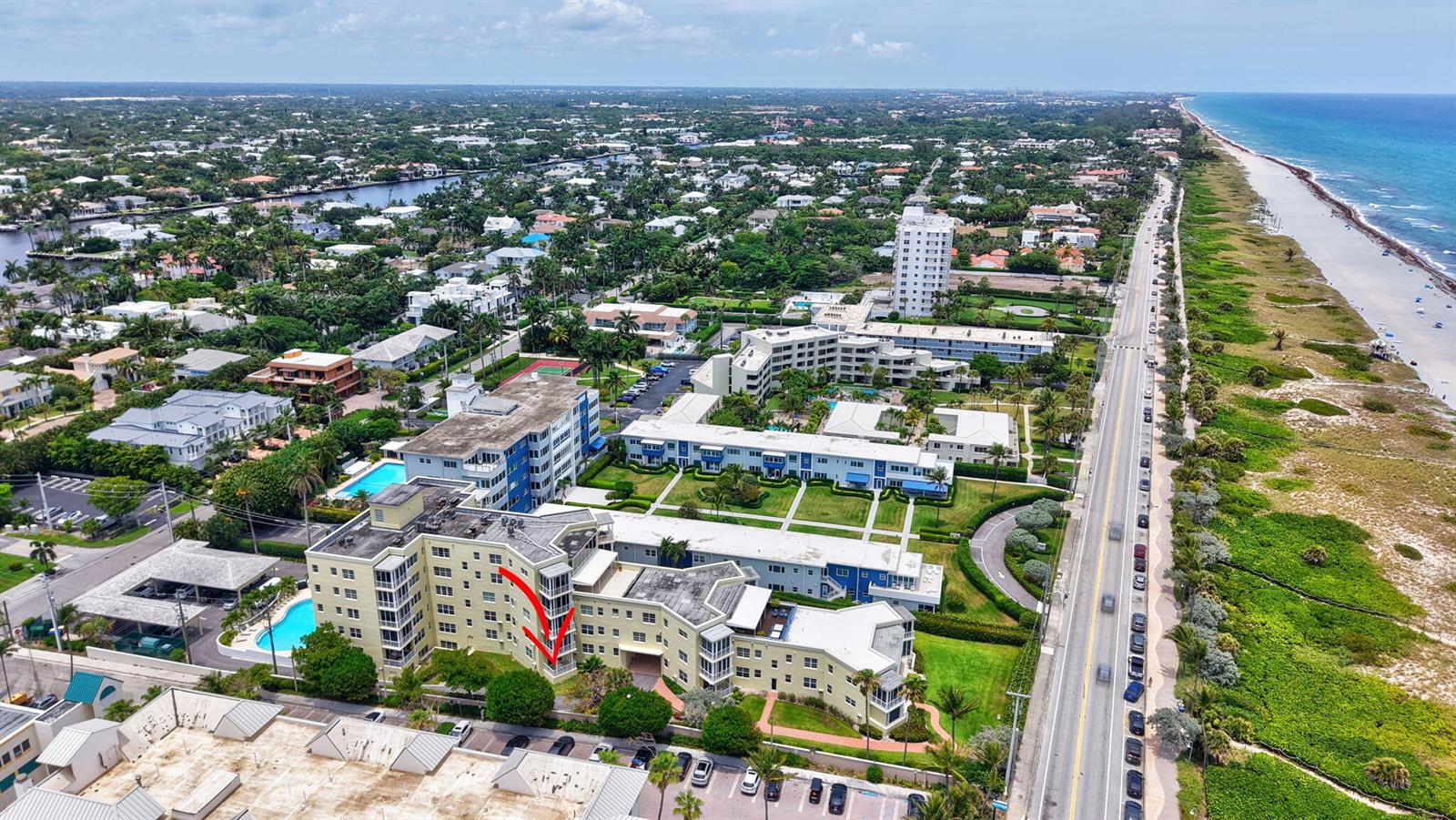 An aerial view shows a multi-story apartment complex with a red arrow pointing to a balcony — 100 N Ocean Boulevard # 105, Delray Beach FL 33483, DELRAY BEACH, FL