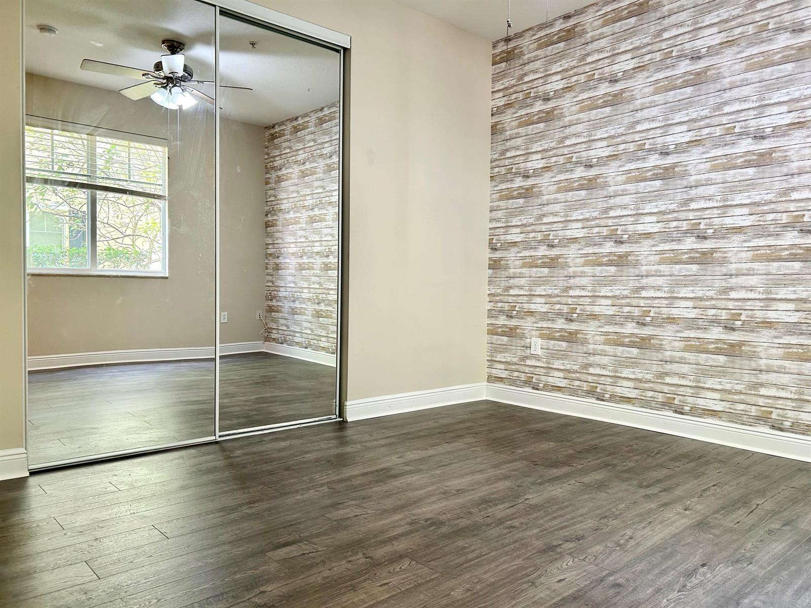 A room features wood-look flooring, a mirrored closet, and a rustic wood-plank accent wall — 3803 NW 5th Terrace, Boca Raton FL 33431, BOCA RATON, FL