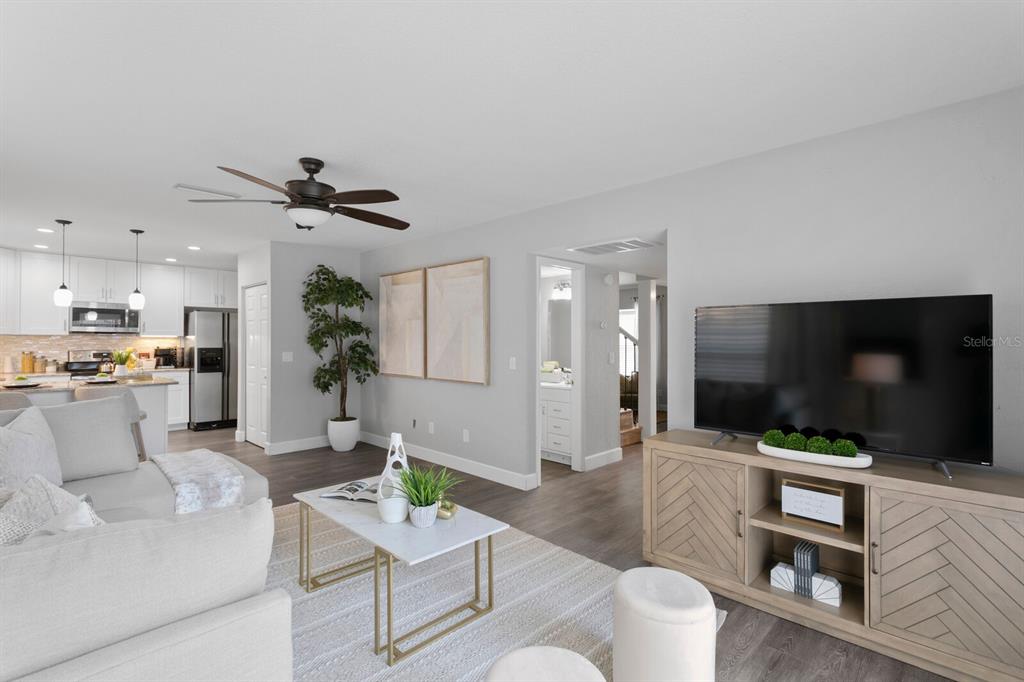 A living room with a television console, a coffee table, and an open-concept kitchen — 14009 DOMINION COURT, TAMPA, FL