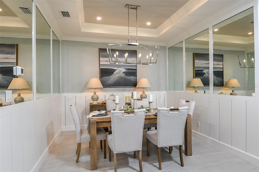 A dining room features a wooden table, upholstered chairs, a chandelier, and mirrored wall panels — 13300 SANTINI CIRCLE, ENGLEWOOD, FL
