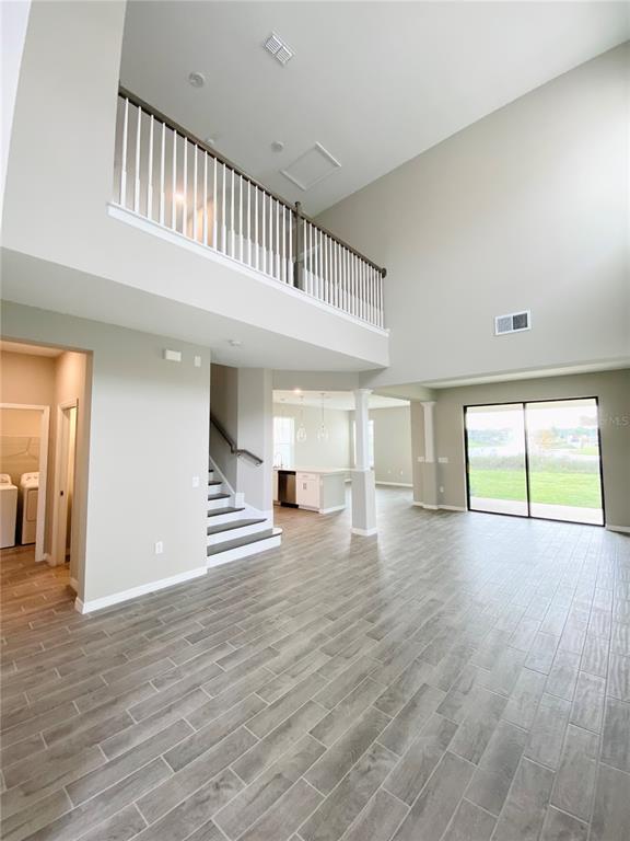A spacious living area features high ceilings, a loft balcony, and light-colored tile flooring — 2307 KESTREL PERCH PLACE, WINTER PARK, FL