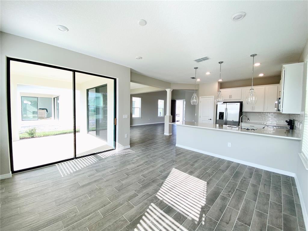A bright kitchen and living area feature gray wood-look tile floors and sliding glass doors — 2307 KESTREL PERCH PLACE, WINTER PARK, FL