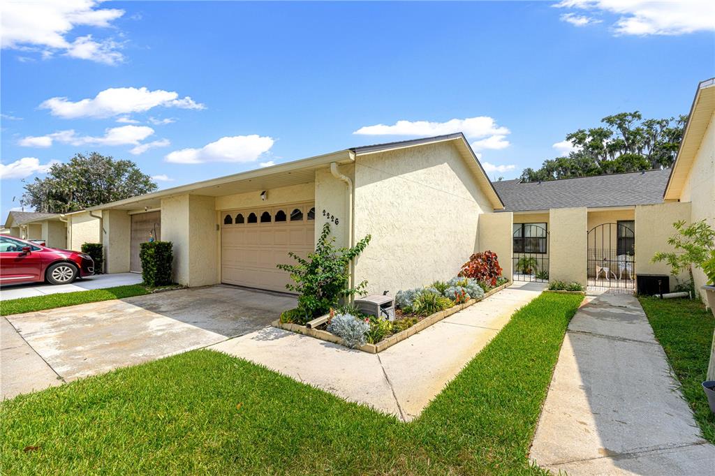 A single-story house with a beige stucco exterior, a garage, and a front walkway — 2226 CYPRESS COVE DRIVE UNIT 2226, TAVARES, FL