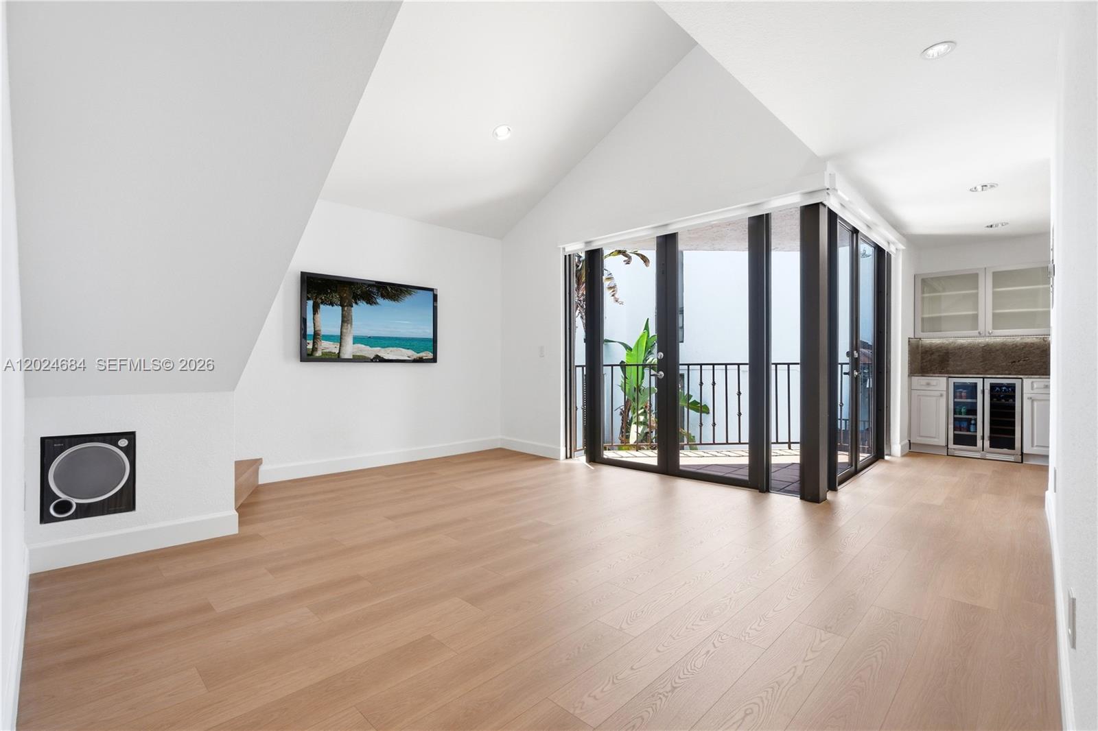A bright room with vaulted ceilings, light wood floors, a wall-mounted television, and a balcony — 3114 Bird Ave # 3114, Miami FL 33133, MIAMI, FL