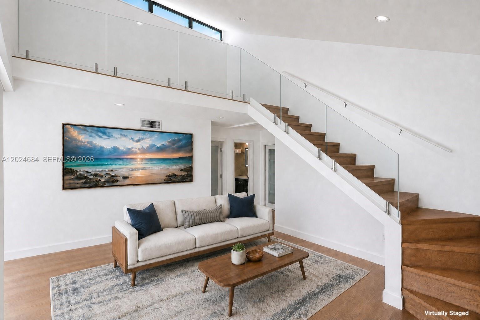 This living room features a white sofa, wooden coffee table, and a staircase with glass railings — 3114 Bird Ave # 3114, Miami FL 33133, MIAMI, FL