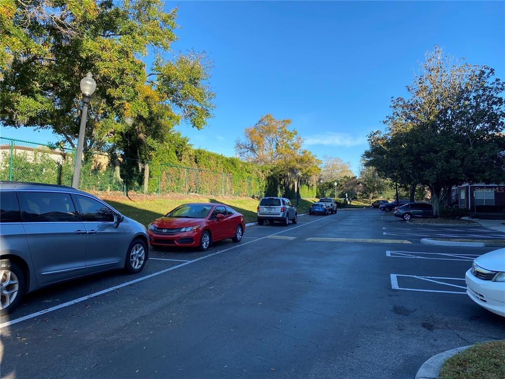 A parking lot with several parked cars and a green fence under a clear sky — 13028 PLANTATION PARK CIRCLE UNIT 1226, ORLANDO, FL