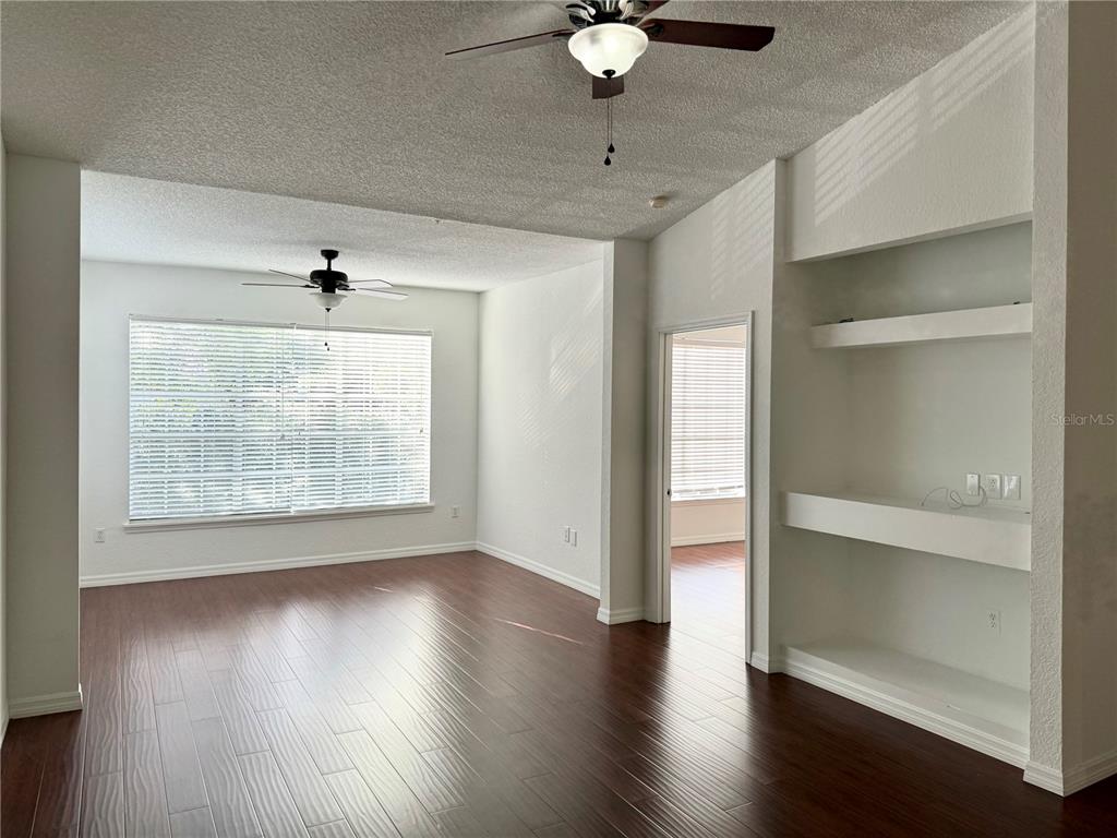 A living room features dark wood flooring, two ceiling fans, and built-in white wall shelves — 13028 PLANTATION PARK CIRCLE UNIT 1226, ORLANDO, FL