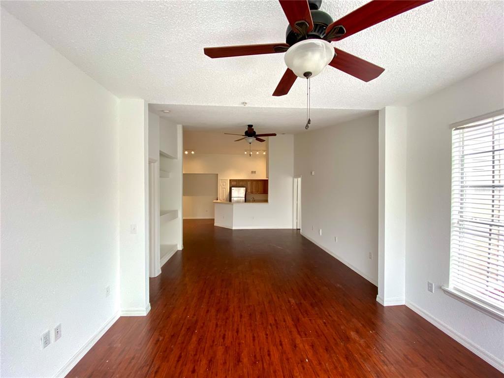 An open-concept living area features dark wood-look flooring, white walls, and two ceiling fans — 13028 PLANTATION PARK CIRCLE UNIT 1226, ORLANDO, FL