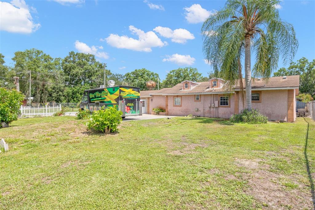 A backyard view of a single-story house with a food truck parked on the driveway — 2442 SHIRAH ROAD, AUBURNDALE, FL