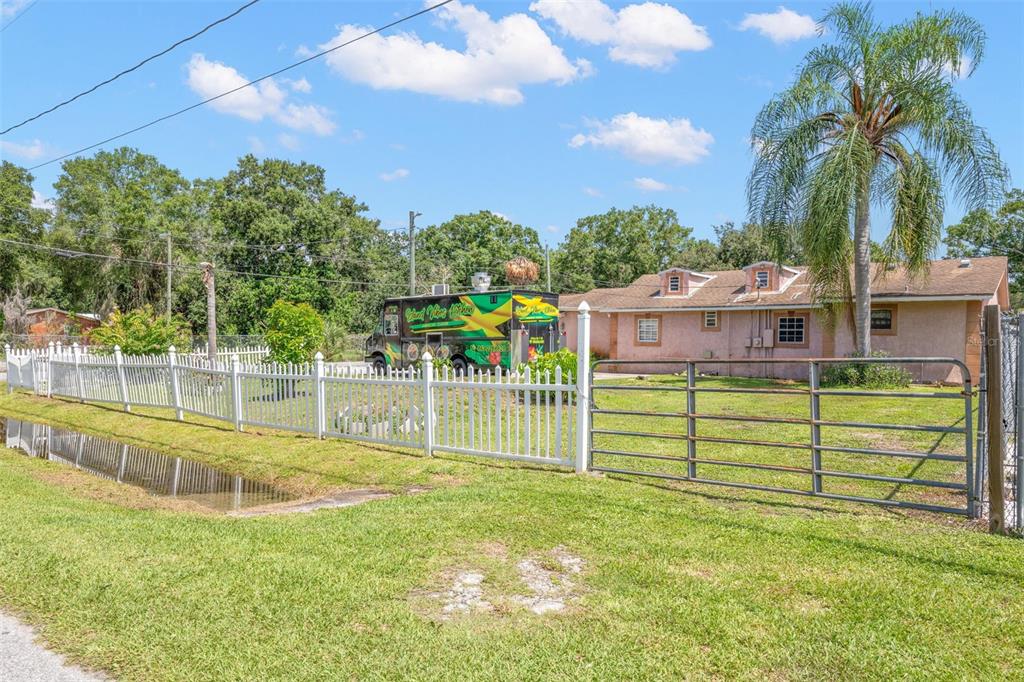 A food truck is parked on a grassy lot next to a house with a fence — 2442 SHIRAH ROAD, AUBURNDALE, FL