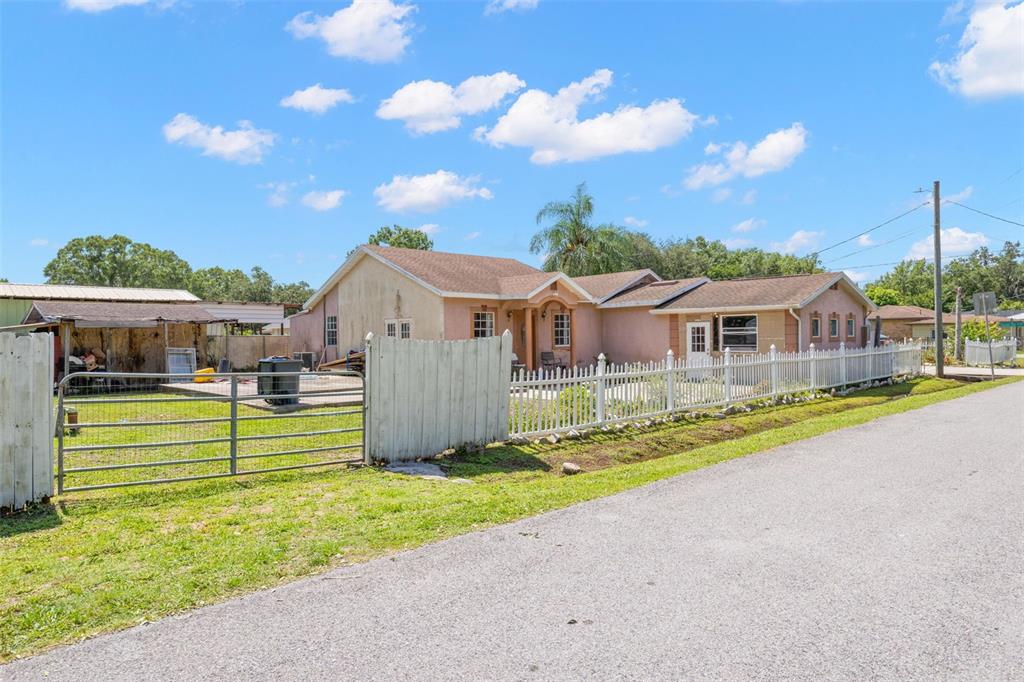 A single-story house with a white picket fence and a metal gate on a street — 2442 SHIRAH ROAD, AUBURNDALE, FL