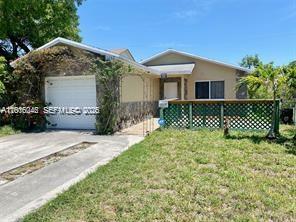 A single-story house features a white garage, stone accents, and a green lattice porch railing — 2345 Douglas St # 0, Hollywood FL 33020, HOLLYWOOD, FL