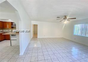 A bright, tiled living area opens to a kitchen with wooden cabinets and a counter — 2345 Douglas St # 0, Hollywood FL 33020, HOLLYWOOD, FL