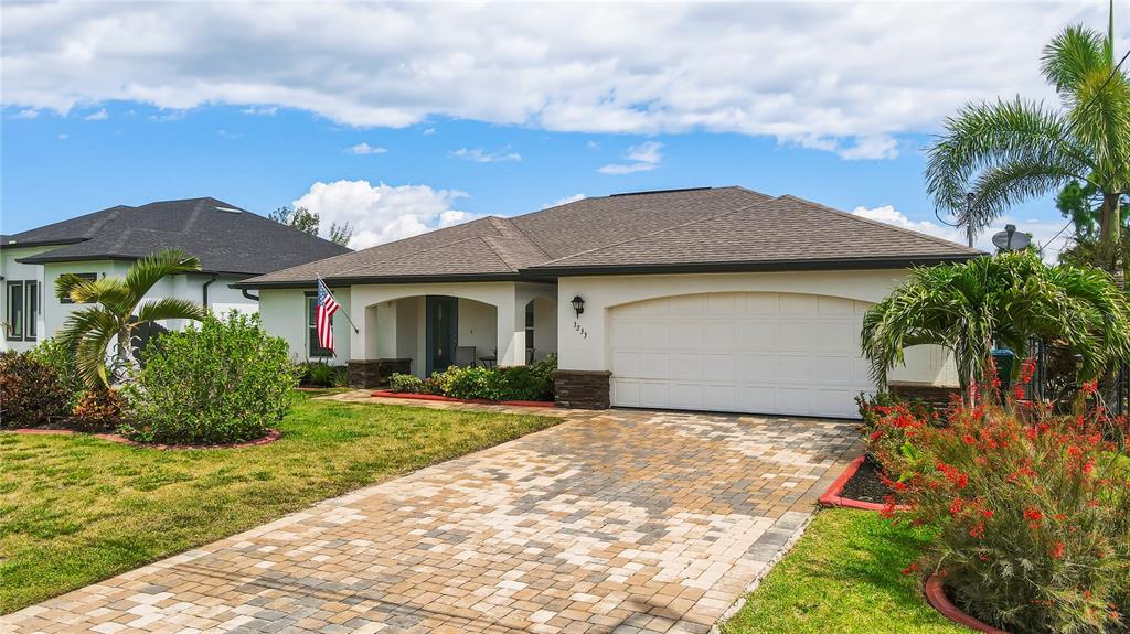 A single-story house with a white stucco facade, stone accents, and a paved walkway — 3233 NW 21ST STREET, CAPE CORAL, FL