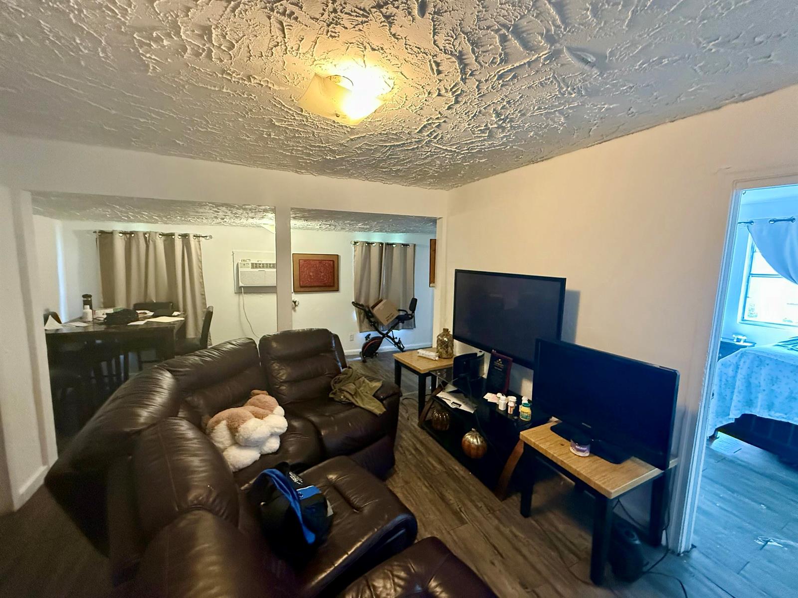 A living room features a brown leather sectional, a television on a stand, and wood-look flooring — 856 SW Ave D, Belle Glade FL 33430, BELLE GLADE, FL