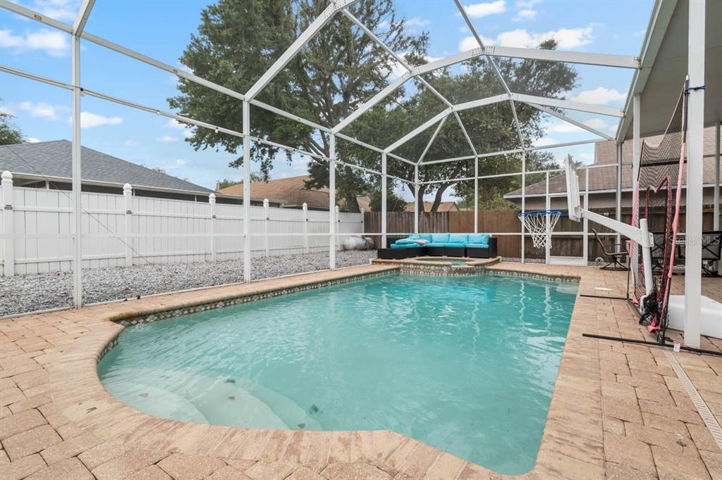 A screened-in swimming pool and spa with a paver deck and white vinyl fence — 9839 LAUREL LEDGE DRIVE, RIVERVIEW, FL