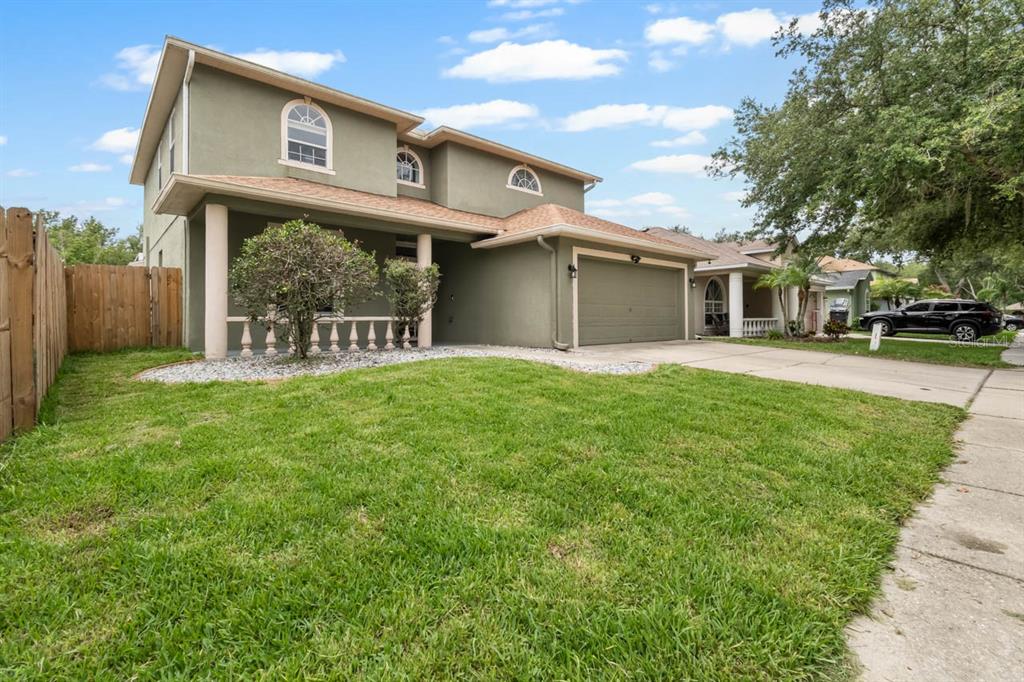 A two-story house with a green stucco exterior, a front porch, and an attached garage — 9839 LAUREL LEDGE DRIVE, RIVERVIEW, FL