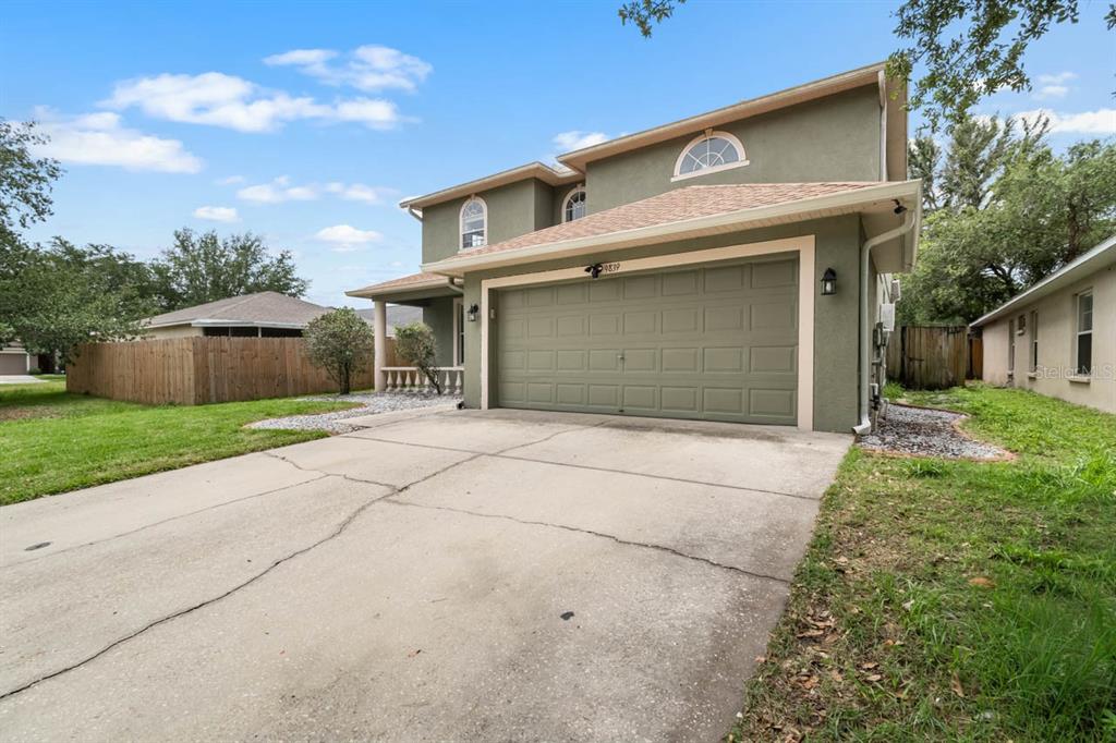 A two-story house with a green stucco exterior, a two-car garage, and a concrete driveway — 9839 LAUREL LEDGE DRIVE, RIVERVIEW, FL