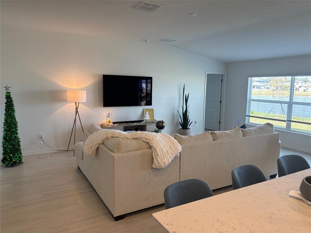 A living room features a sectional sofa, wall-mounted television, floor lamp, and tile flooring — 8823 SUNSET PARK TRAIL, PARRISH, FL