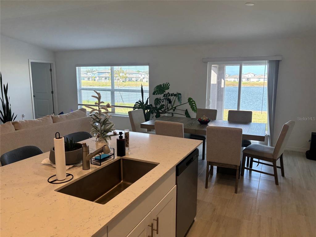 A kitchen island with a sink overlooks a dining area and a view of water — 8823 SUNSET PARK TRAIL, PARRISH, FL