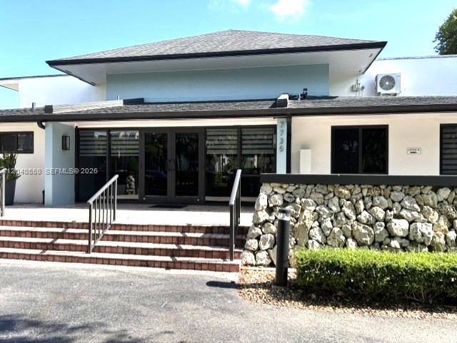 The exterior of a commercial building features a stone wall, glass doors, and stairs — 7785 SW 86th St # 113, Miami FL 33143, MIAMI, FL
