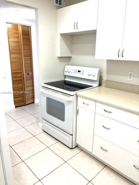 A kitchen features white cabinets, a white electric stove, and light-colored tile flooring — 7785 SW 86th St # 113, Miami FL 33143, MIAMI, FL