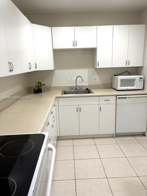 A kitchen with white cabinets, a stainless steel sink, a microwave, and tile flooring — 7785 SW 86th St # 113, Miami FL 33143, MIAMI, FL