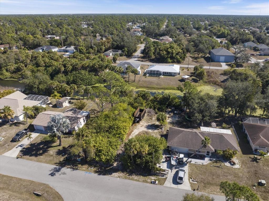 An aerial view shows several suburban houses, a wooded lot, and a small pond — NATRONA DRIVE, NORTH PORT, FL