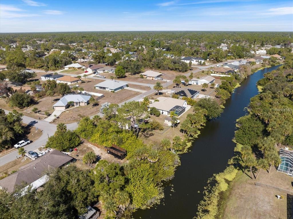 An aerial view shows a residential neighborhood with houses situated along a narrow canal — NATRONA DRIVE, NORTH PORT, FL
