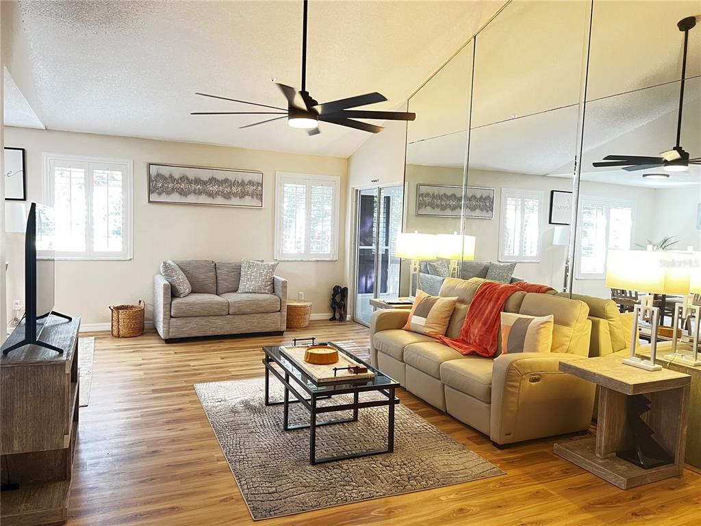 A living room features light wood flooring, a mirrored wall, and two neutral-colored sofas — 821 LOCH CALDER UNIT 27, APOPKA, FL