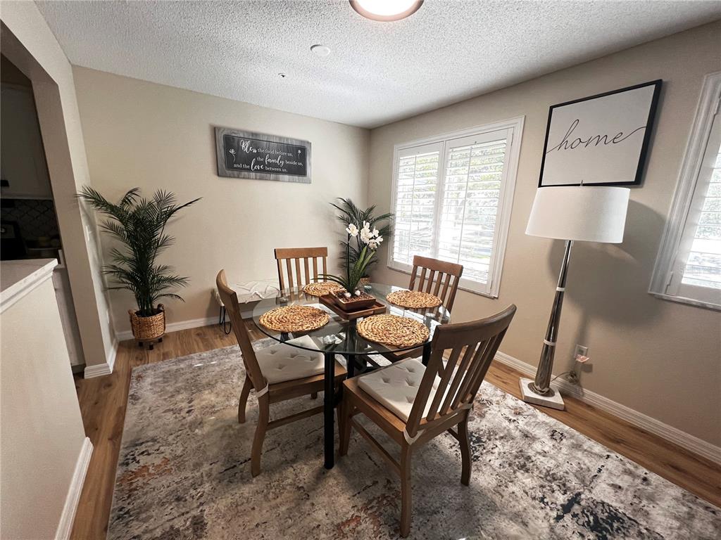 A dining room features a glass table with four wooden chairs on a patterned rug — 821 LOCH CALDER UNIT 27, APOPKA, FL