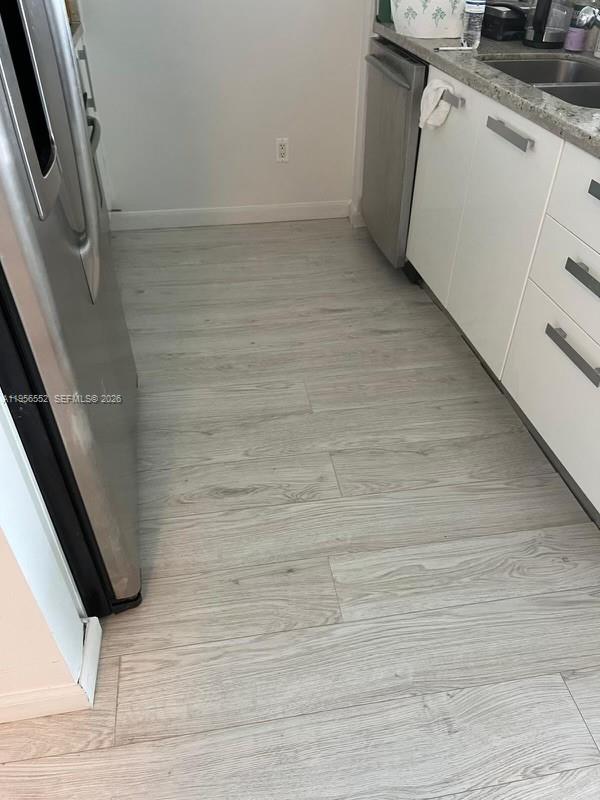 A kitchen features light wood-look flooring, white cabinets, and stainless steel appliances — 601 NE 36th St # 1305, Miami FL 33137, MIAMI, FL