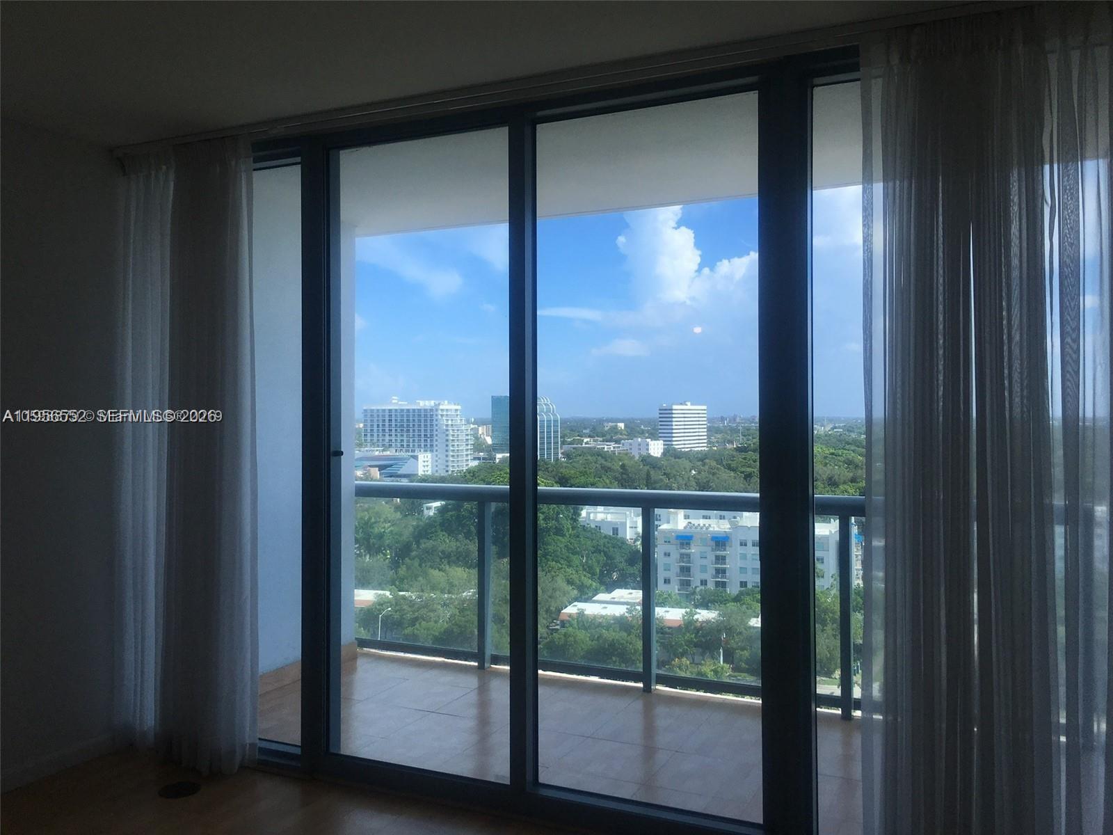 A room with floor-to-ceiling glass sliding doors opening onto a balcony with city views — 601 NE 36th St # 1305, Miami FL 33137, MIAMI, FL