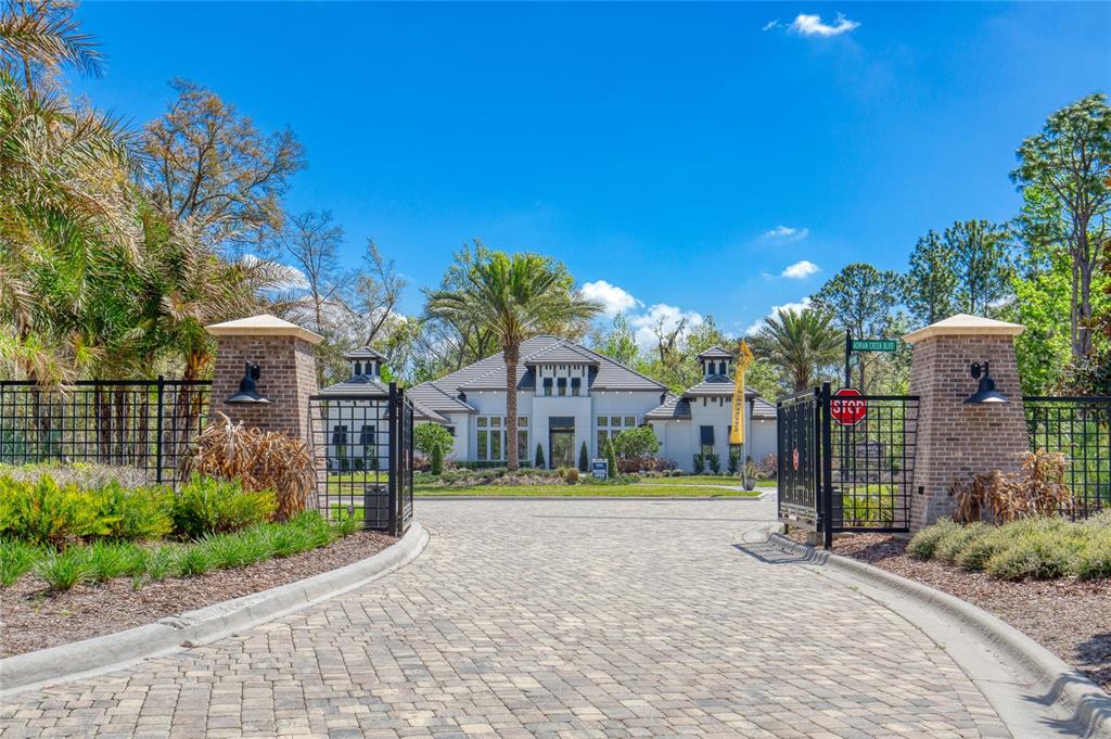 A gated entrance with brick pillars leads to a large house with a paved driveway — 1801 ADRIAN CREEK BOULEVARD, PORT ORANGE, FL