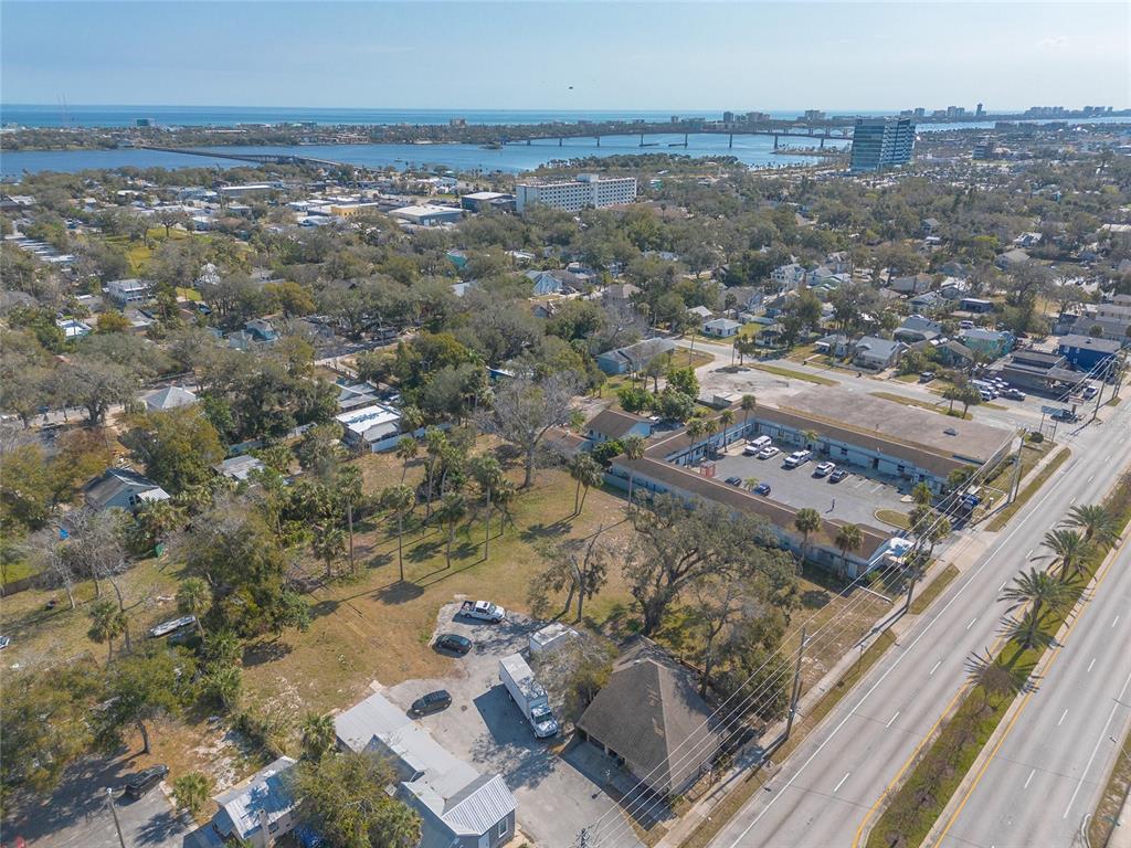 An aerial view shows a commercial building, a parking lot, and surrounding residential properties — 629 N RIDGEWOOD AVENUE, DAYTONA BEACH, FL