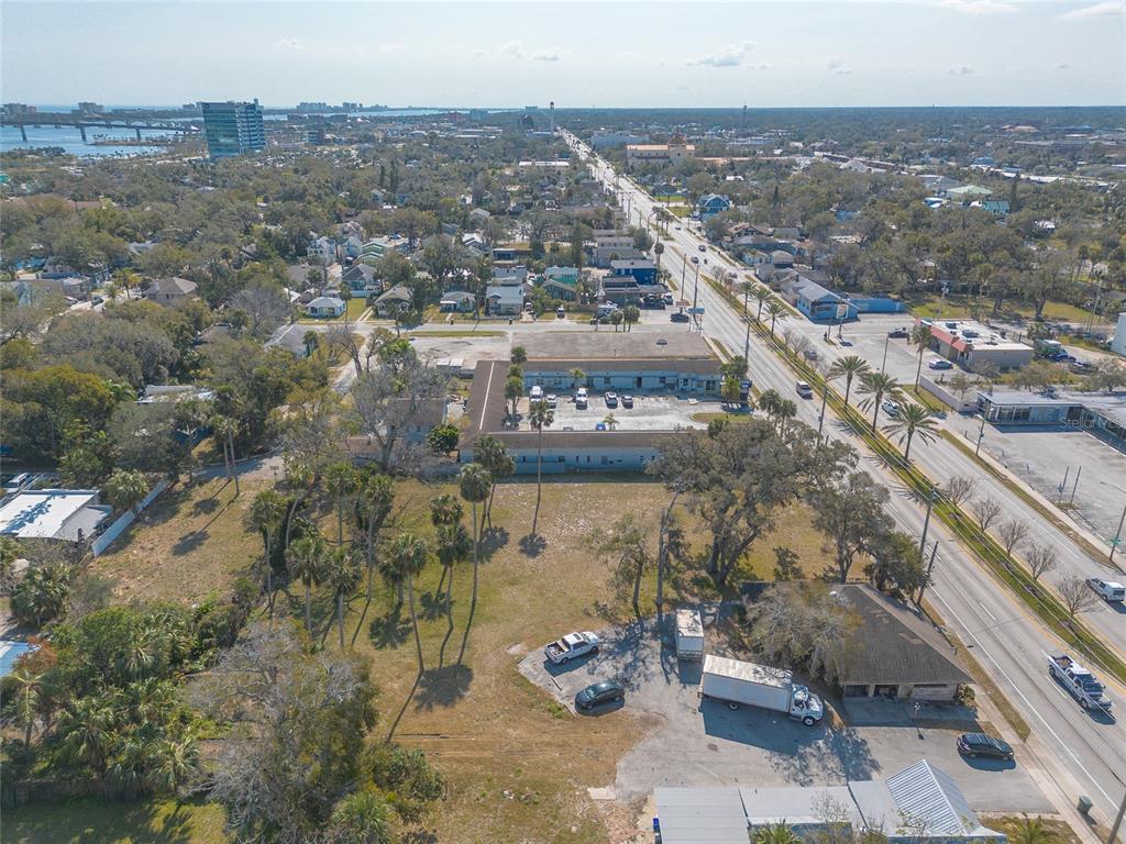 An aerial view shows a commercial building, a large vacant lot, and a nearby road — 629 N RIDGEWOOD AVENUE, DAYTONA BEACH, FL