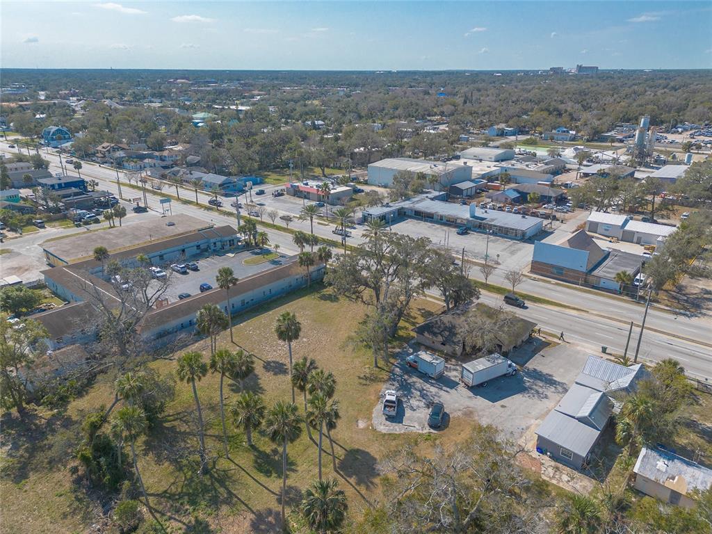 An aerial view shows a commercial property with parking lots, palm trees, and surrounding buildings — 629 N RIDGEWOOD AVENUE, DAYTONA BEACH, FL