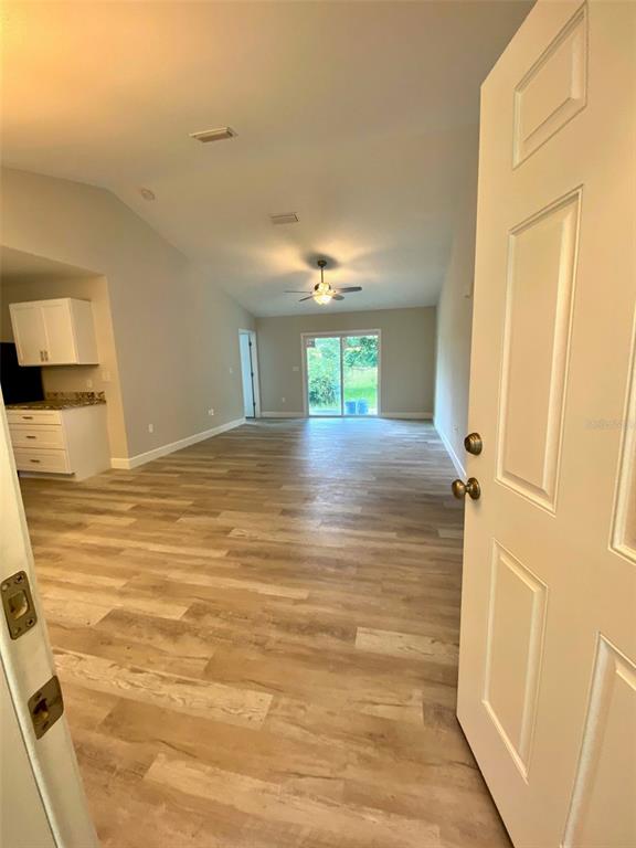An open-concept living area with light wood-look flooring and a sliding glass door — 8555 NW 210TH STREET, MICANOPY, FL