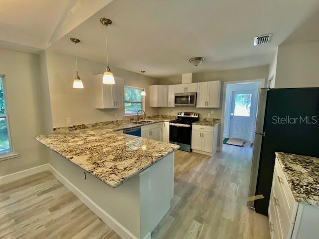 A kitchen features white cabinets, granite countertops, a kitchen island, and light wood-look flooring — 8555 NW 210TH STREET, MICANOPY, FL