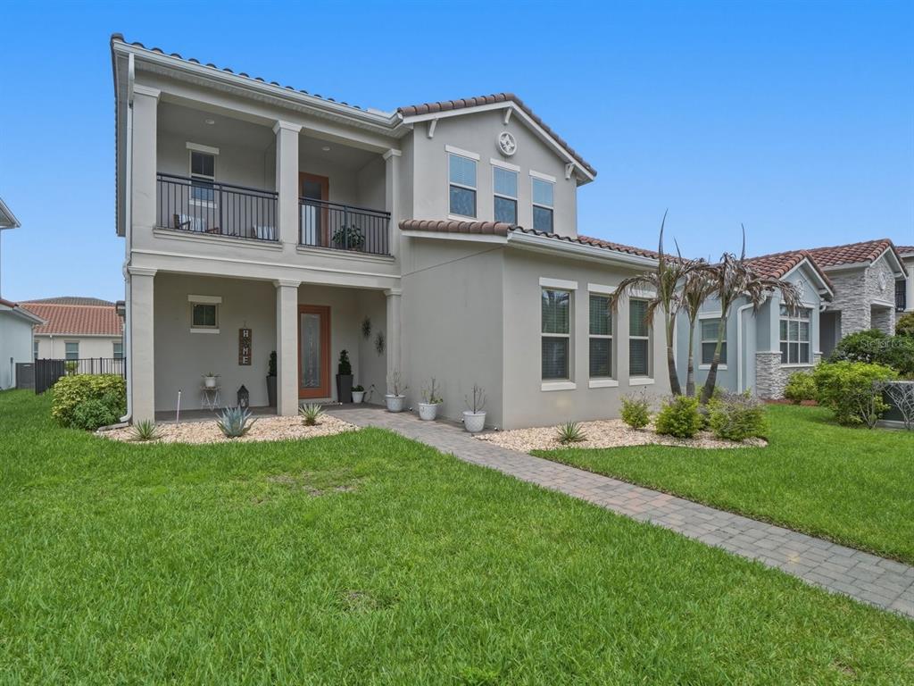 A two-story house with a covered front porch, balcony, and a paved walkway — 9448 MERE PARKWAY, ORLANDO, FL