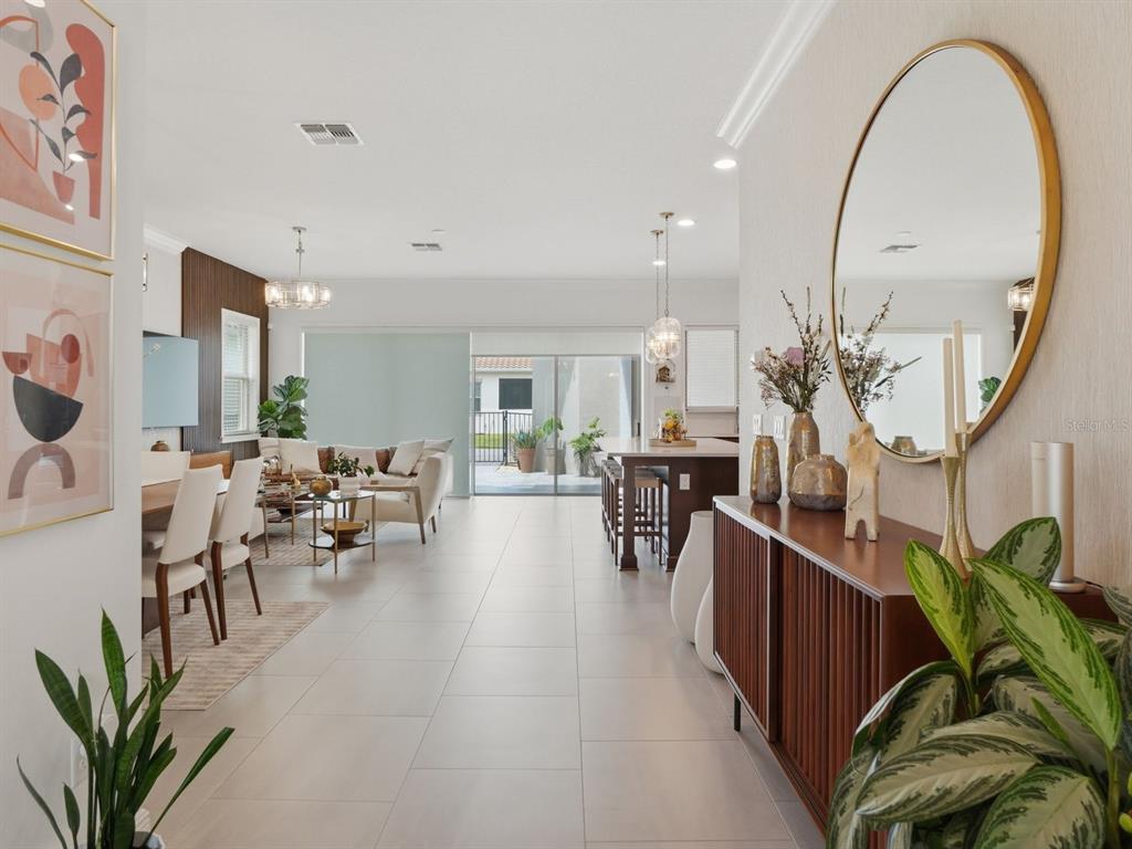 An open-concept living and dining area features tile floors, a kitchen island, and sliding doors — 9448 MERE PARKWAY, ORLANDO, FL