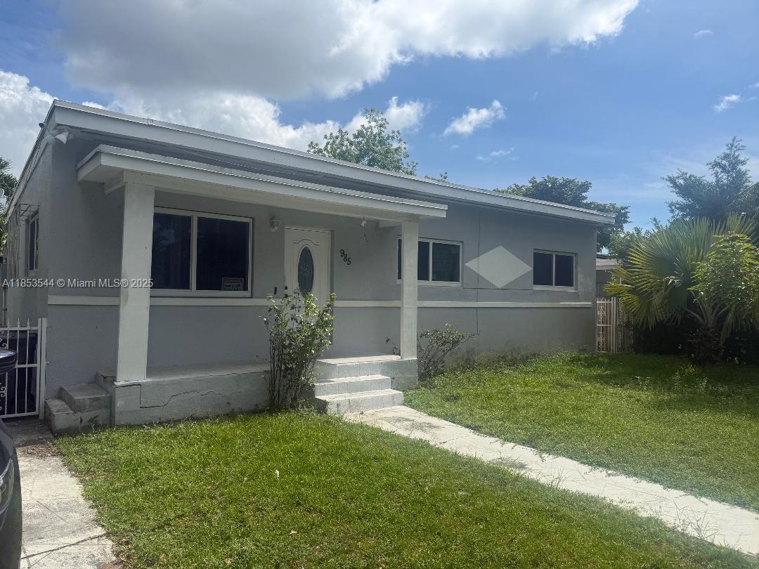 A single-story gray house features a covered front porch, white trim, and a grassy lawn — 985 NE 146th St, North Miami FL 33161, NORTH MIAMI, FL