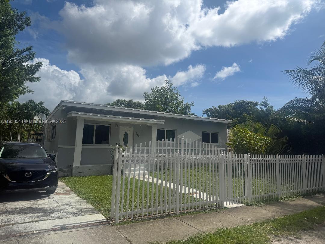 A single-story house with a gray exterior, white fence, and a car in the driveway — 985 NE 146th St, North Miami FL 33161, NORTH MIAMI, FL