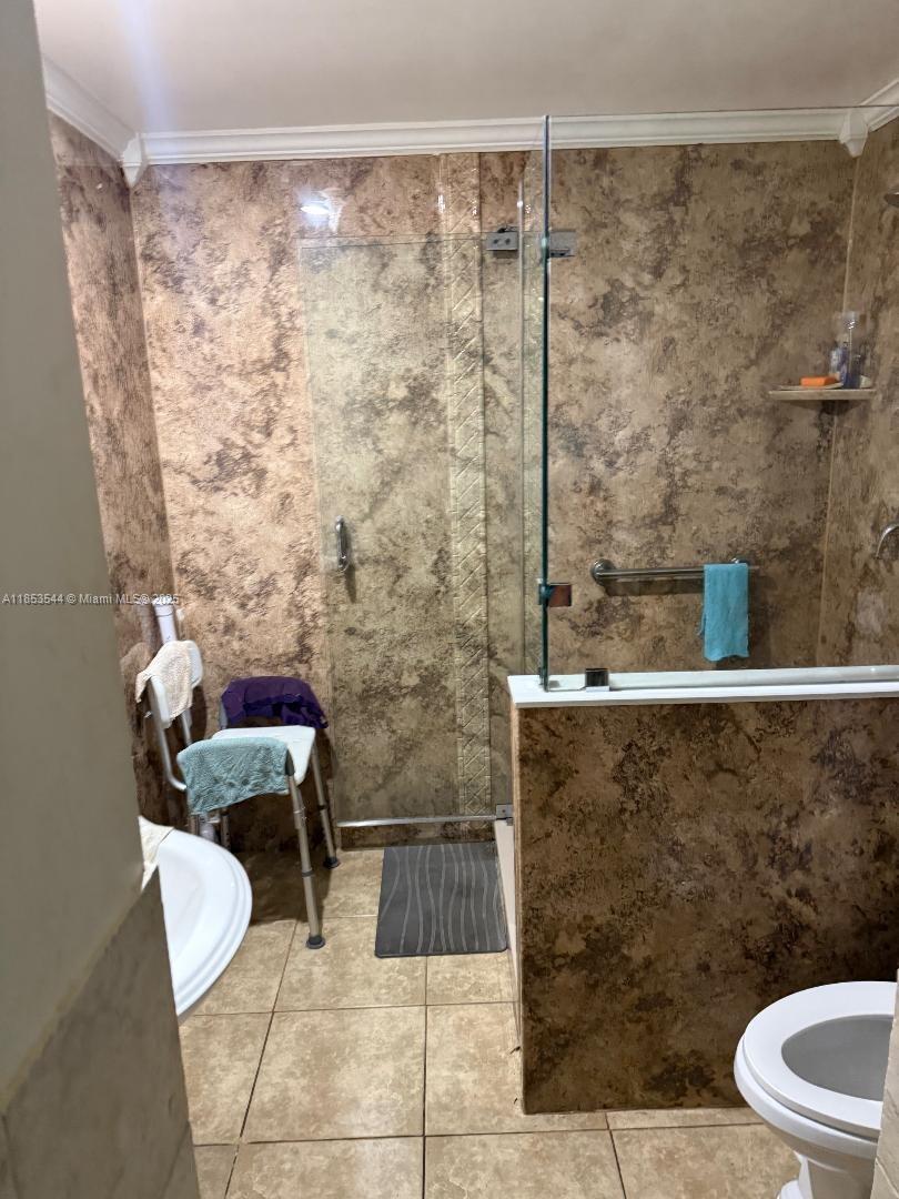 A bathroom features a walk-in shower with brown textured walls and a white shower chair — 985 NE 146th St, North Miami FL 33161, NORTH MIAMI, FL
