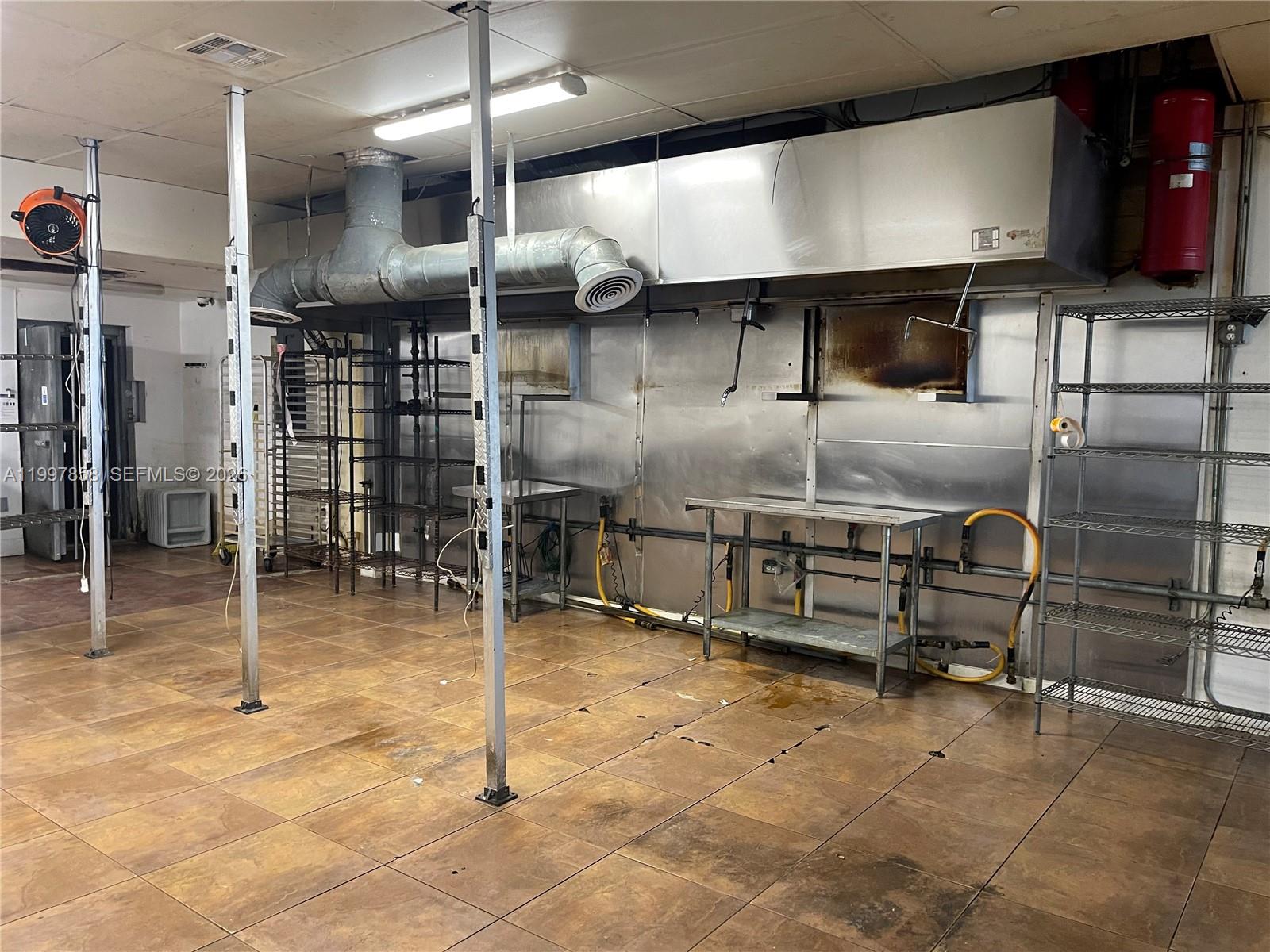 A commercial kitchen features stainless steel wall panels, a ventilation hood, and metal shelving units — 1777 SW 3 AV, Miami FL 33129, MIAMI, FL