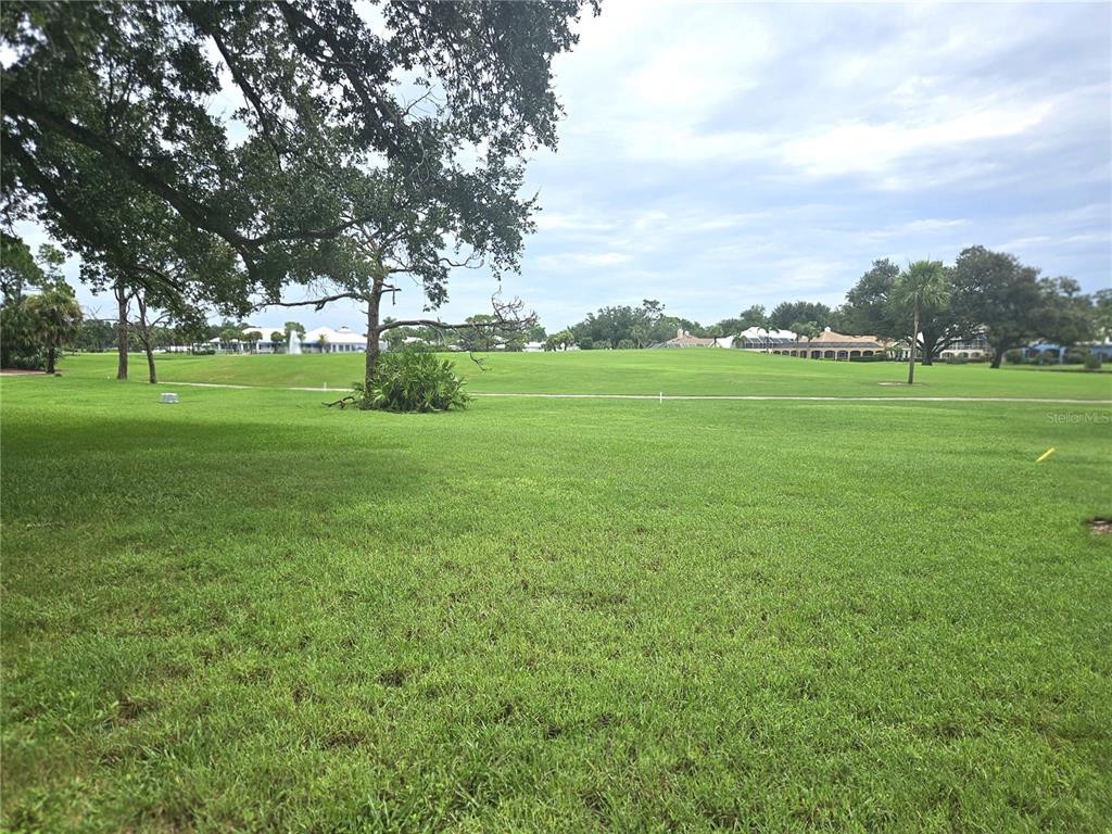 A large, grassy lawn stretches toward a golf course with trees and distant houses — 418 CERROMAR COURT UNIT 257, VENICE, FL
